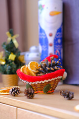 Festive Christmas and New Year decorative card template.
Snowman, Christmas tree with gold decorations, wicker basket with dried oranges and pine cones on a wooden table in the frame.