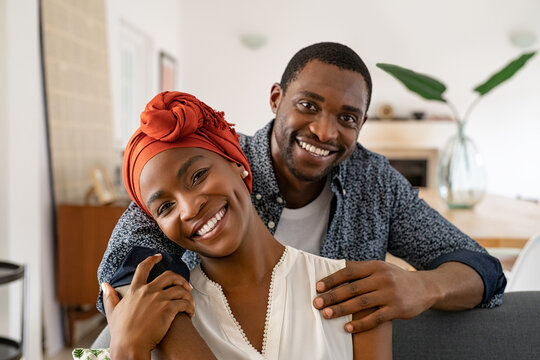 Cheerful black couple embracing at home