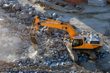 A hydraulic breaker is mounted on the excavator. It is powered by an auxiliary hydraulic system...