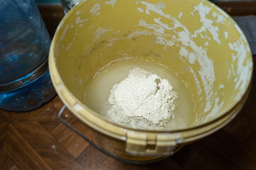 White putty in a bucket of water. Preparation of mortar for finishing walls and ceilings in the apartment. Repair in the house. DIY. Selective focus