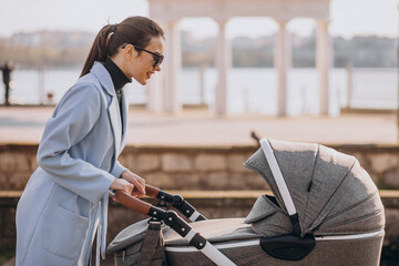 Young asian woman mother, walking with baby stroller in park