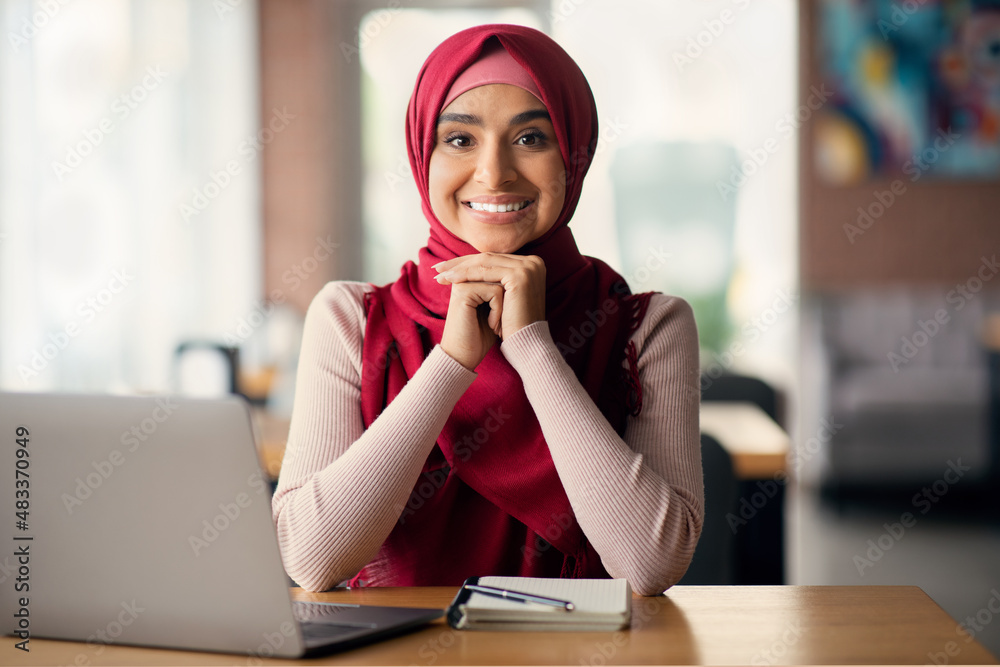 Wall mural attractive young woman in headscarf student using laptop at cafe