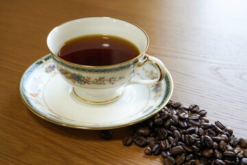 高級感のある陶器のティーカップに注がれたコーヒーとコーヒー豆