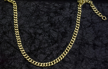 Gold jewelry. Gold chains on black leather background