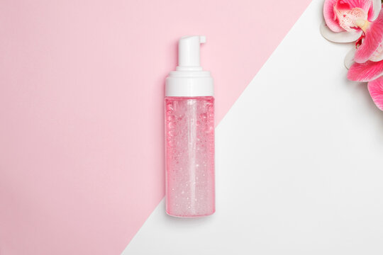Facial foam in a plastic bottle with an orchid on the background.