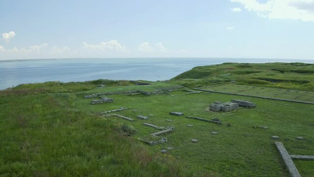 Ancient buildings and ruins of castle on river and fields background. Drone video. Olivia National Historical and Archaeological Reserve