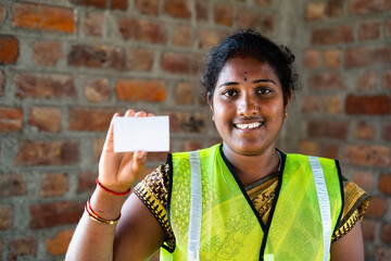 Indian happy smiling labour women showing empty card by lookig at camera - concept of empoyee id...