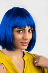 Beauty, fashion, makeup concept. Close-up studio portrait of beautiful and sexy woman in blue wig and yellow t-shirt looking to the camera. Woman with blue eyes and pink lipstick with sensual look