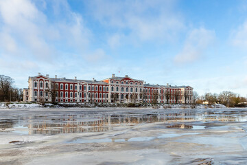 Angled view to frozen river Lielupe and to Jelgava Palace (Latvian: Jelgavas pils) at sunny winter day in Jelgava, Latvia. The largest Baroque-style place in the Baltic States in winter.  