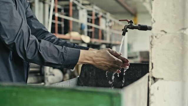 A man washes his hands from dirt and oil. Old abandoned factory of the times of the USSR.