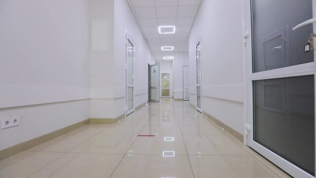 Corridors of a modern hospital. The camera pans along the empty hallway of the hospital. The empty, bright corridor of the clinic. Interior of a modern clinic