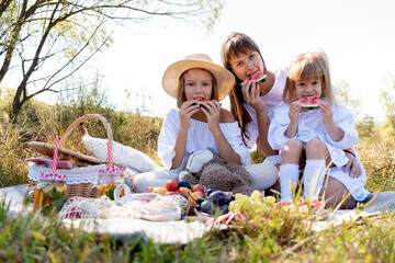 Mom with daughters on a picnic in nature the field eat watermelon. Concept maternal care and love.