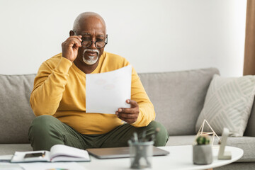 Senior African Male Working With Papers Wearing Eyeglasses Sitting Indoor - Powered by Adobe