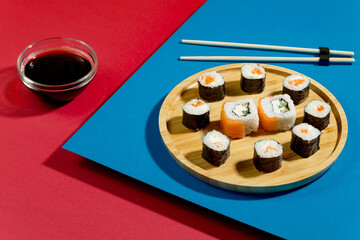 Sushi on a plate on a bright, colored background.