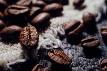Macrophotography of coffee beans lie on textured wood and burlap. Fresh harvest aromatic coffee. Selective focusing. Back for cafe, restaurant or coffee shop.