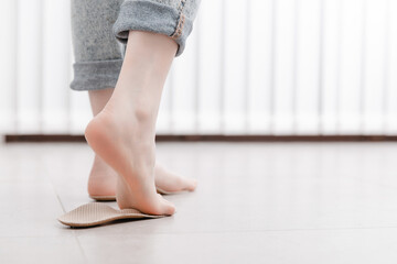 Woman fitting orthopedic insole indoors, close up. Girl holding an insole next to foot at home....