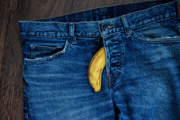 A banana coming out from fly of blue jeans as a flaccid penis. Manhood, penis, erection and erectile dysfunction concept image. - obrazy, fototapety, plakaty