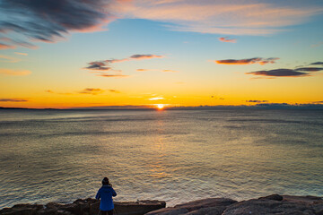 photographer capturing the sunrise on the Atlantic ocean horizon in Acadia National Park, Maine, USA
