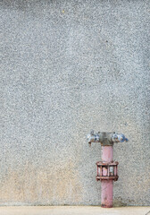 Fire hose point Installed on a dotted plaster wall The appearance of the pipe has a dull and old color. Indicates a relatively long service life. slightly rusted