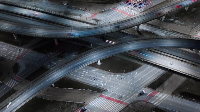 Aerial time lapse traffic jam interchange road at night, drone shot top view roadway intersection in city in evening. Timelapse cars driving busy junction highway in fast motion