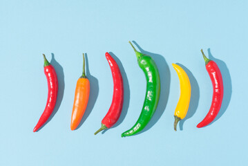 Hot chili red, yellow, orange peppers on blue background, natural spices, top view, pop-art style...