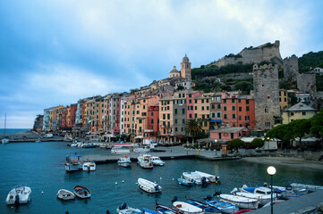 Port with small boats, waterfront and colorful houses with towers in the evening in Portovenere in the Cinque Terre (Italy).