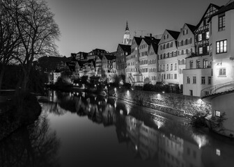 Fototapeta na wymiar “Neckarfront“ illuminated historic facades of old town of Tuebingen on Neckar River in southern Germany an a winter evening with colorful reflections, Hölderlin Tower and Church