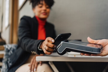 Black woman using smartphone for contactless payment in cafe