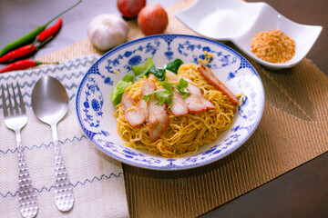 Egg Noodles with Barbeque Pork in Chinese Style Plates on a Wooden Table with Tea and .garnish