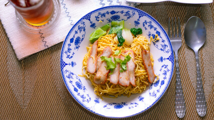 Egg Noodles with Barbeque Pork in Chinese Style Plates on a Wooden Table with Tea and .garnish