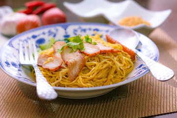 Egg Noodles with Barbeque Pork in Chinese Style Plates on a Wooden Table with Tea and .garnish