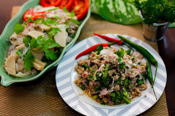 Spicy vietnamese sausages salad and Spicy minced pork.(Thai food) With onion, garlic, red pepper on a black wooden table