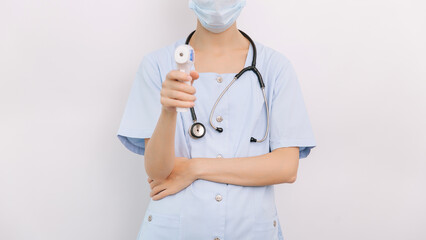 Temperature measurement gun in doctor hands. Close-up shot of doctor wearing protective surgical...