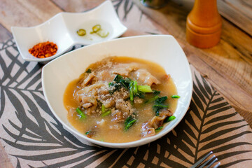 Wide Rice Noodles with pork in Gravy Sauce in white Plate or what we call " Rat-na " in Thai.