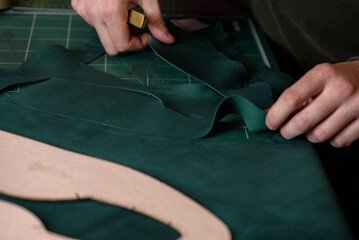 Shoemaker cutting suede leather with craft knife for handmade shoes in workshop. Making bespoke...