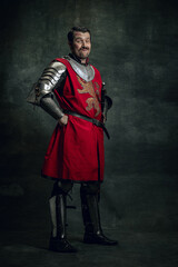 Portrait of smiling man in image of medieval warrior with dirty wounded face wearing equipment...