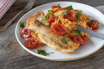 Healthy fish dish with natural pan fried fillet and italian risotto with tomatoes on a plate