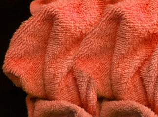 crumpled bright orange bath towels. wavy texture on black background
