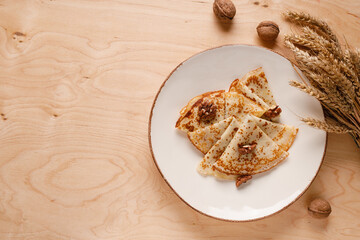 Homemade pancakes with walnuts on a wooden table. Pancake day. Decorated with ears of wheat.