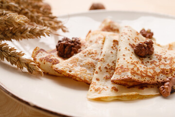 Homemade pancakes with walnuts on a wooden table. Pancake day. Decorated with ears of wheat.