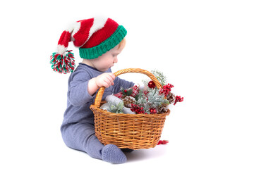 Fototapeta na wymiar Kid in a Christmas hat with a basket of Christmas toys on a white background.