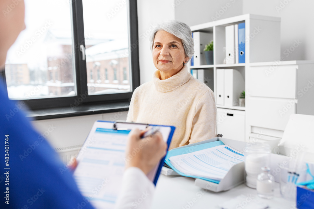 Sticker medicine, health and vaccination concept - doctor with clipboard and senior woman at hospital