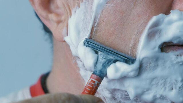 Man bleeding while shaving face with blade scared