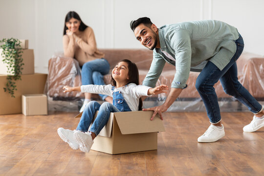 Happy arab father riding daughter in cardboard box