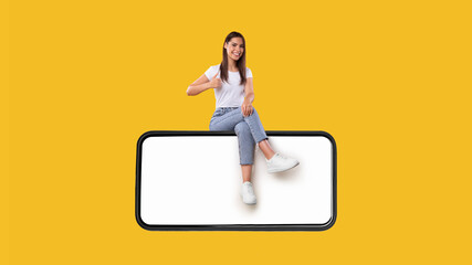 Woman sitting on white blank smartphone screen showing thumbs up