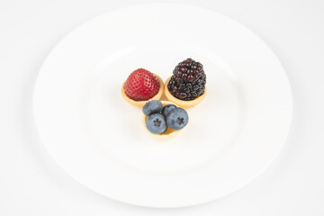 Blackberry, blueberry and strawberry in a waffle basket on a white background. Vitamins and wholesome foods