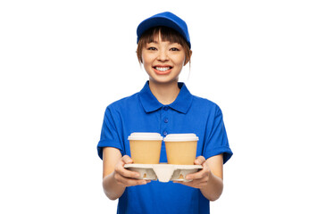 service and job concept - happy smiling delivery woman in blue uniform with takeaway hot drinks in disposable coffee cups over white background