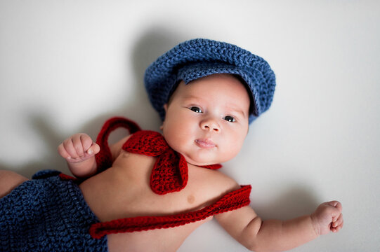 Soft picture of a beautiful baby boy 1-3 months laying on white bedding wearing crochet costume, newborn photography