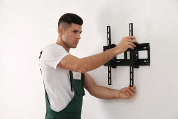 Professional technician installing TV bracket on wall indoors