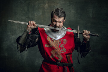 Comic portrait of funny medieval warrior or knight with dirty wounded face holding sword isolated...